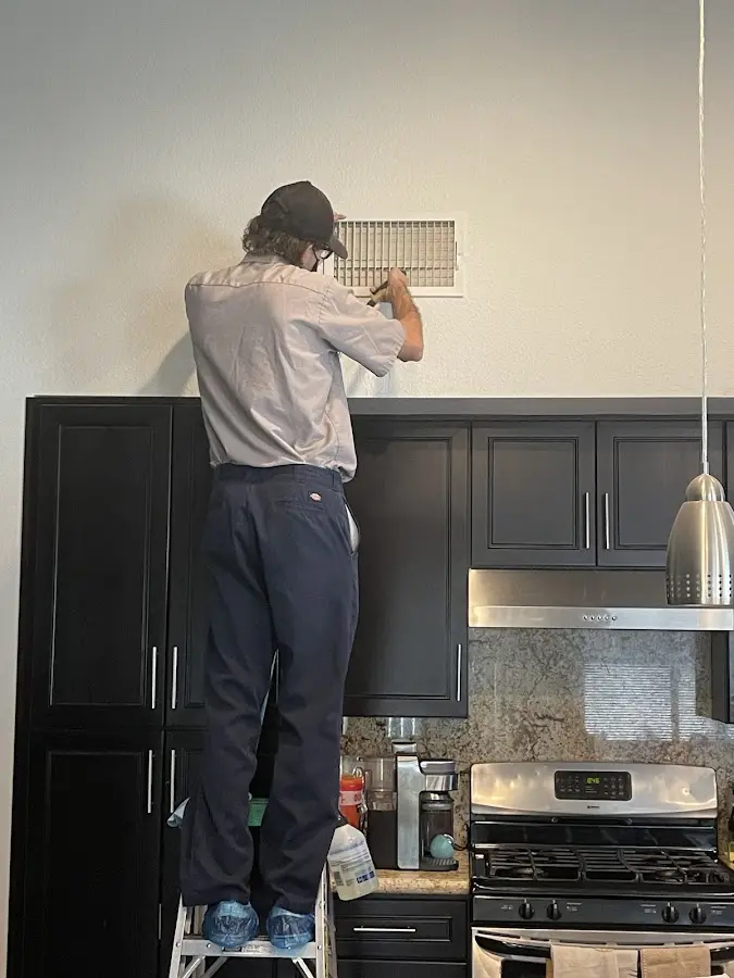 Technician inspecting an air vent during HVAC service in Amory